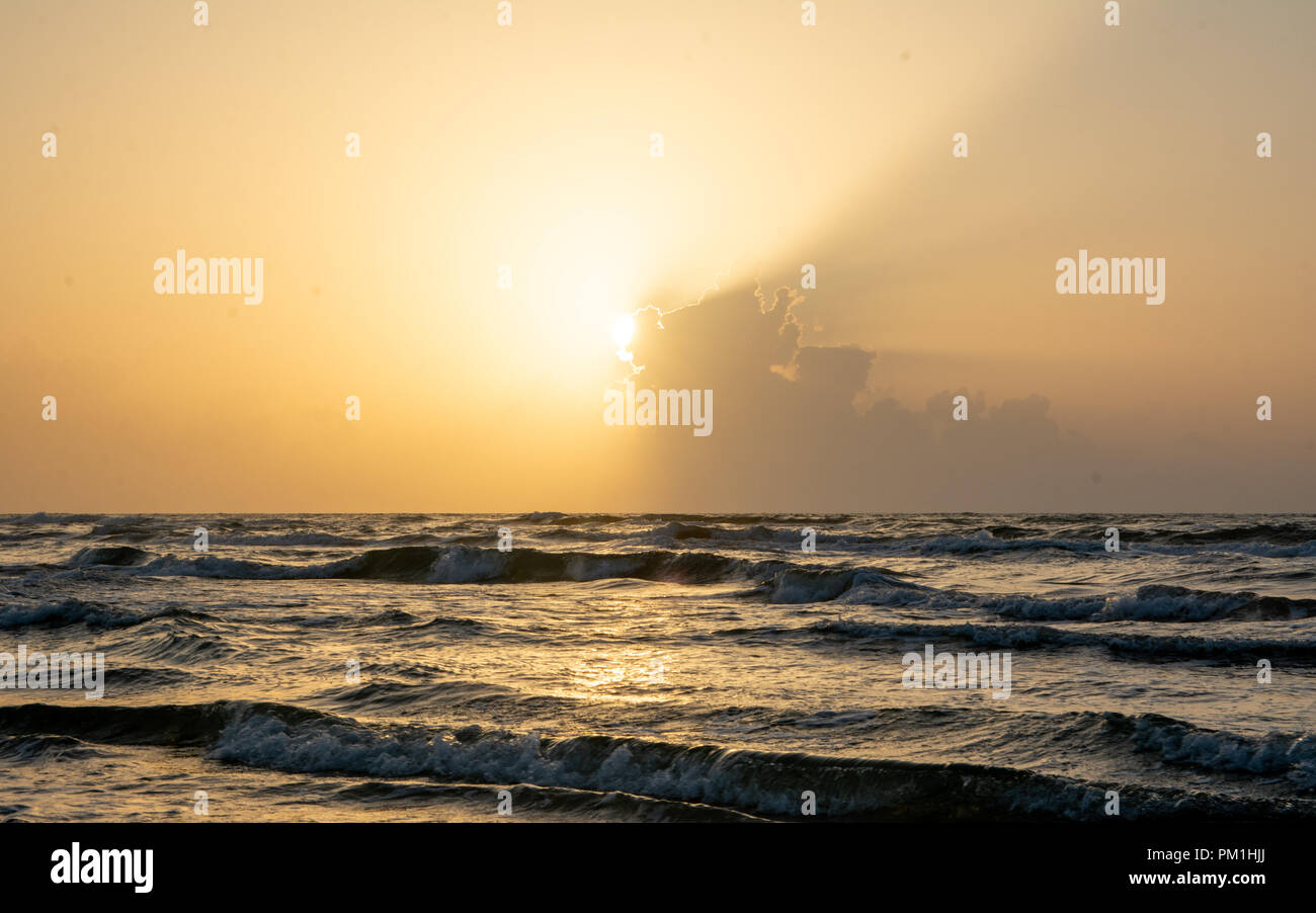 Le lever du soleil sur les nuages à l'horizon sur mer calme avec plage et des vagues Banque D'Images