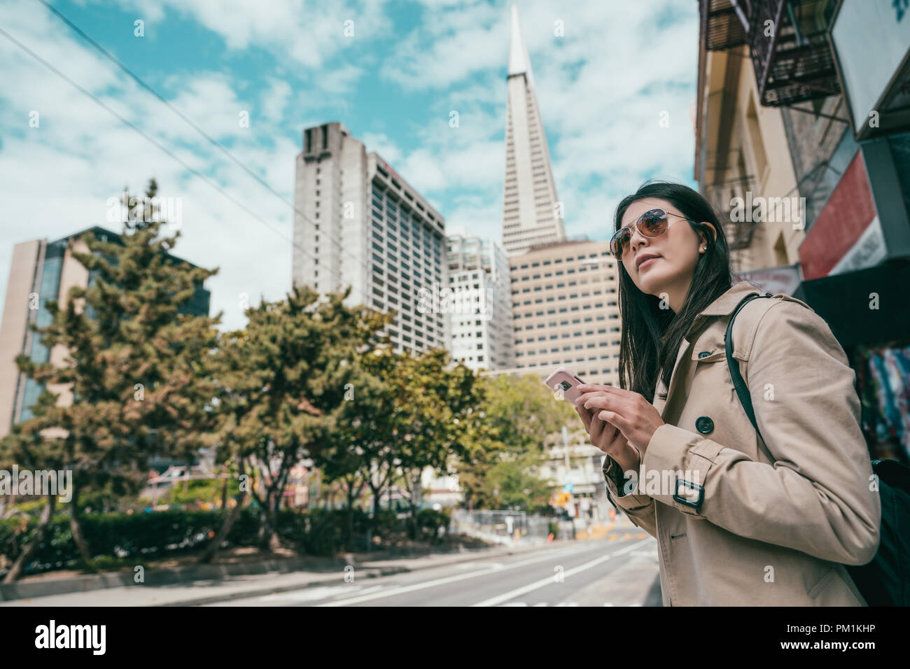 Jolie femme recherche par son téléphone portable et debout dans la rue, dans une belle ville de Morden. Banque D'Images