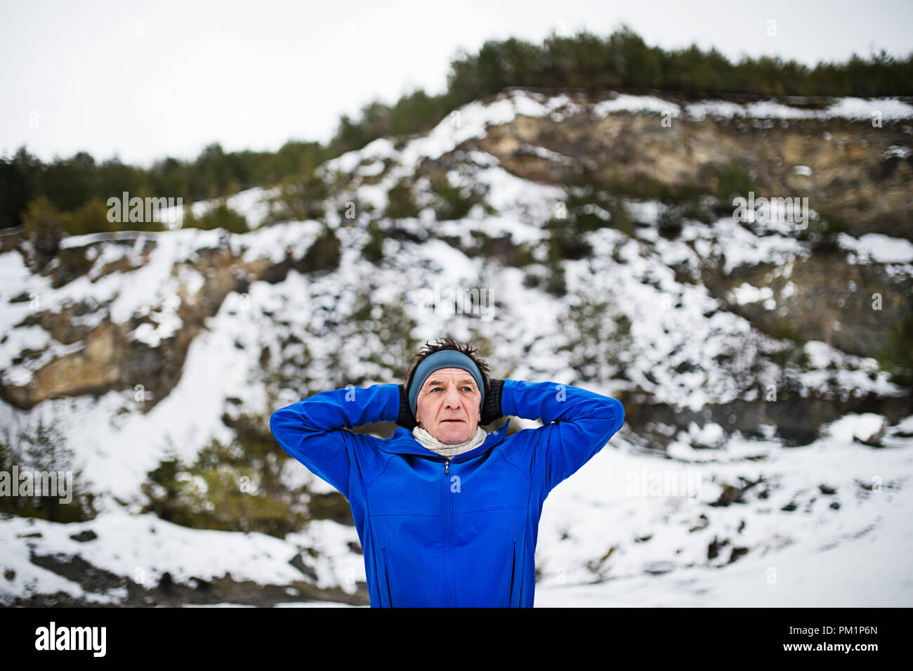 Une ceinture-up portrait of senior man stretching avant la course en hiver la nature. Banque D'Images