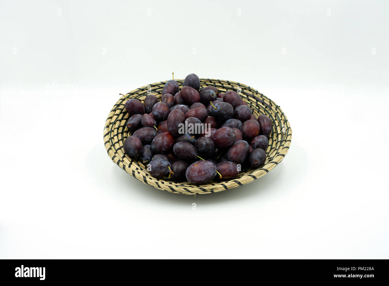 Les prunes délicieux dans un panier décoratif bast. Studio shot on white background Banque D'Images Les prunes délicieux dans un panier décoratif bast. Studio shot on white background Banque D'Images