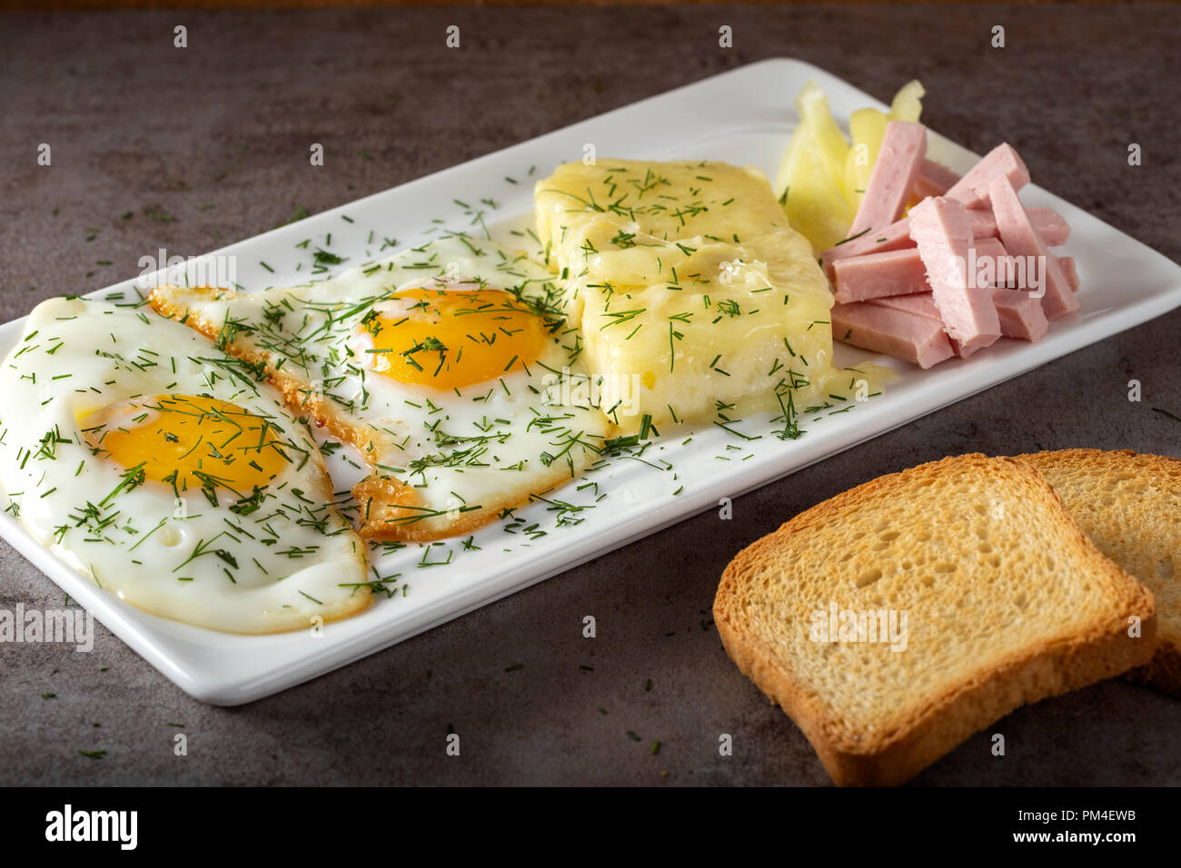 Oeufs au plat avec du fromage fondu et du cas roumain appelé quelques parizer avec toast Banque D'Images