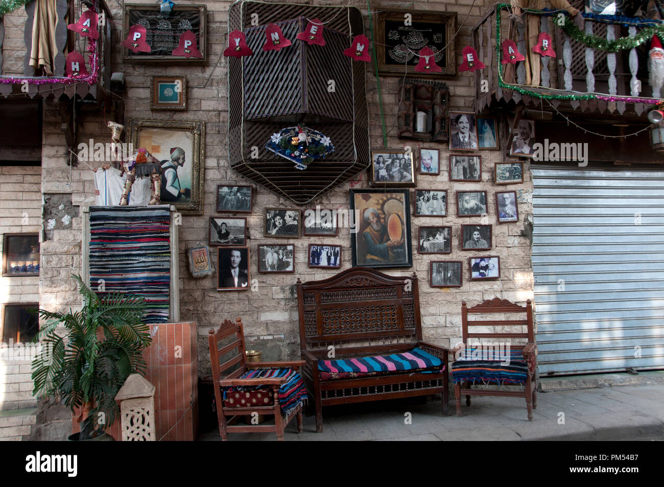 L'Égypte, Le Caire 2014. Khan al-Khalilli , ancienne zone islamique. Café en plein air table et chaises avec bonne année signe et photos anciennes sur les murs. Banque D'Images