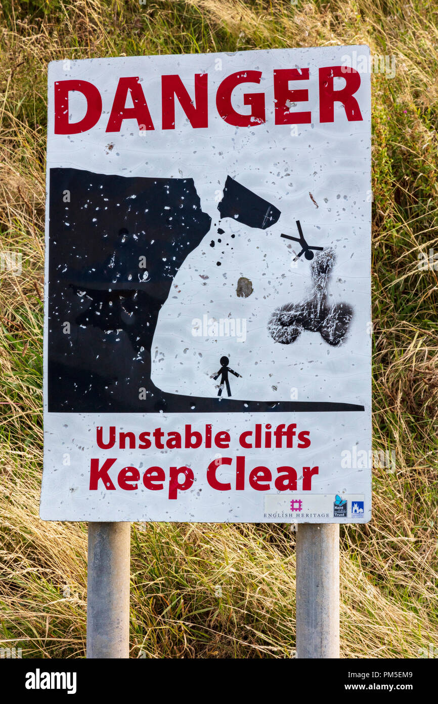 Un panneau d'avertissement, de danger falaises instables se tenir à l'écart, un dessin montre une falaise tombant en ruine et d'une personne, un symbole graffiti phallique a été ajoutée, Herne Bay, Kent, UK Banque D'Images