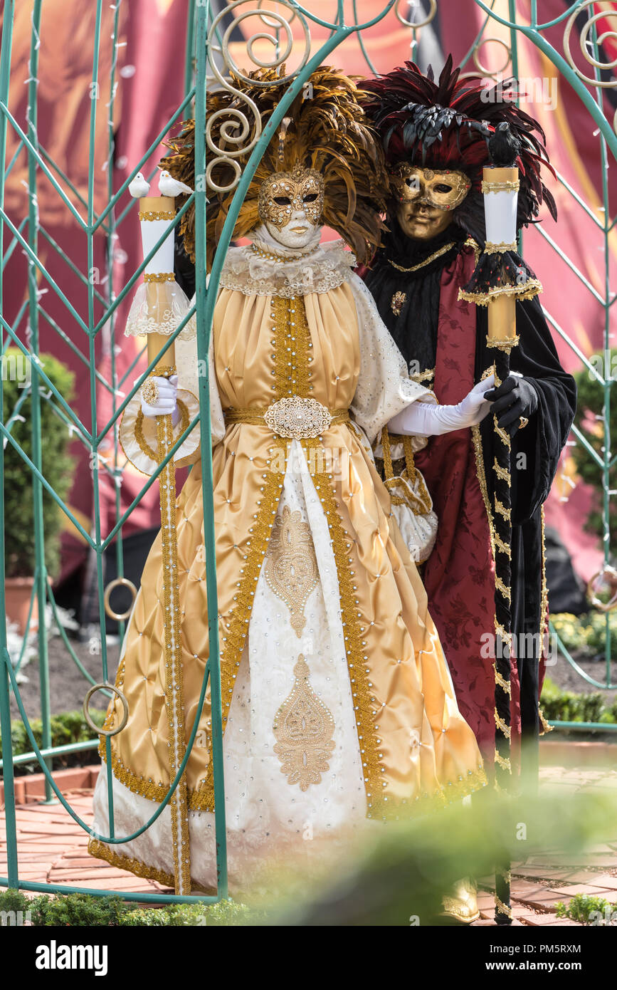 Une femme en blanc et or costume carnaval vénitien se tient à côté d'un homme mystérieux dans un costume noir et or Banque D'Images