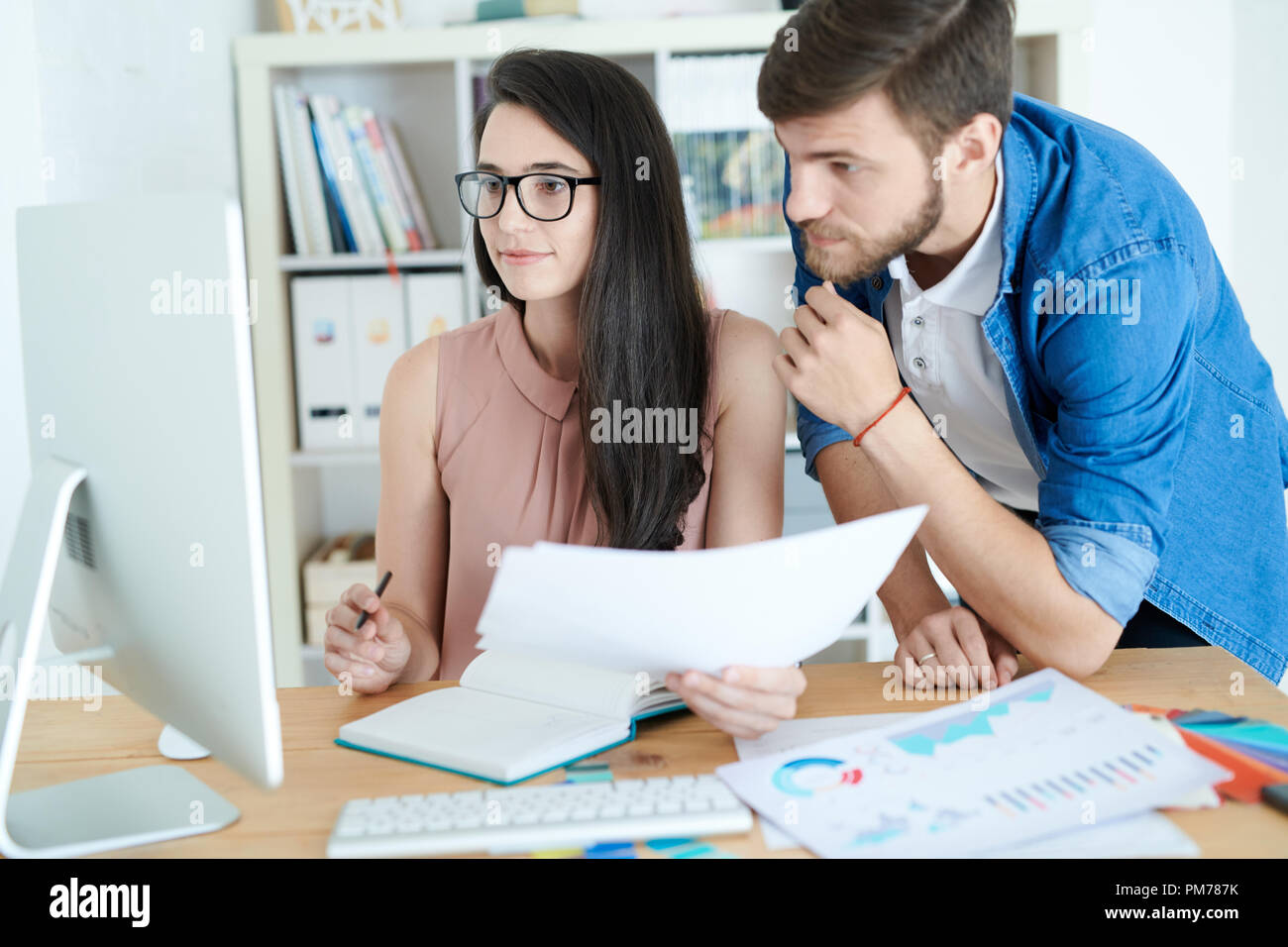 Portrait de deux jeunes gens, l'homme et de la femme, à l'aide d'ordinateur et de discuter de projets tout en travaillant au bureau de conception moderne studio Banque D'Images