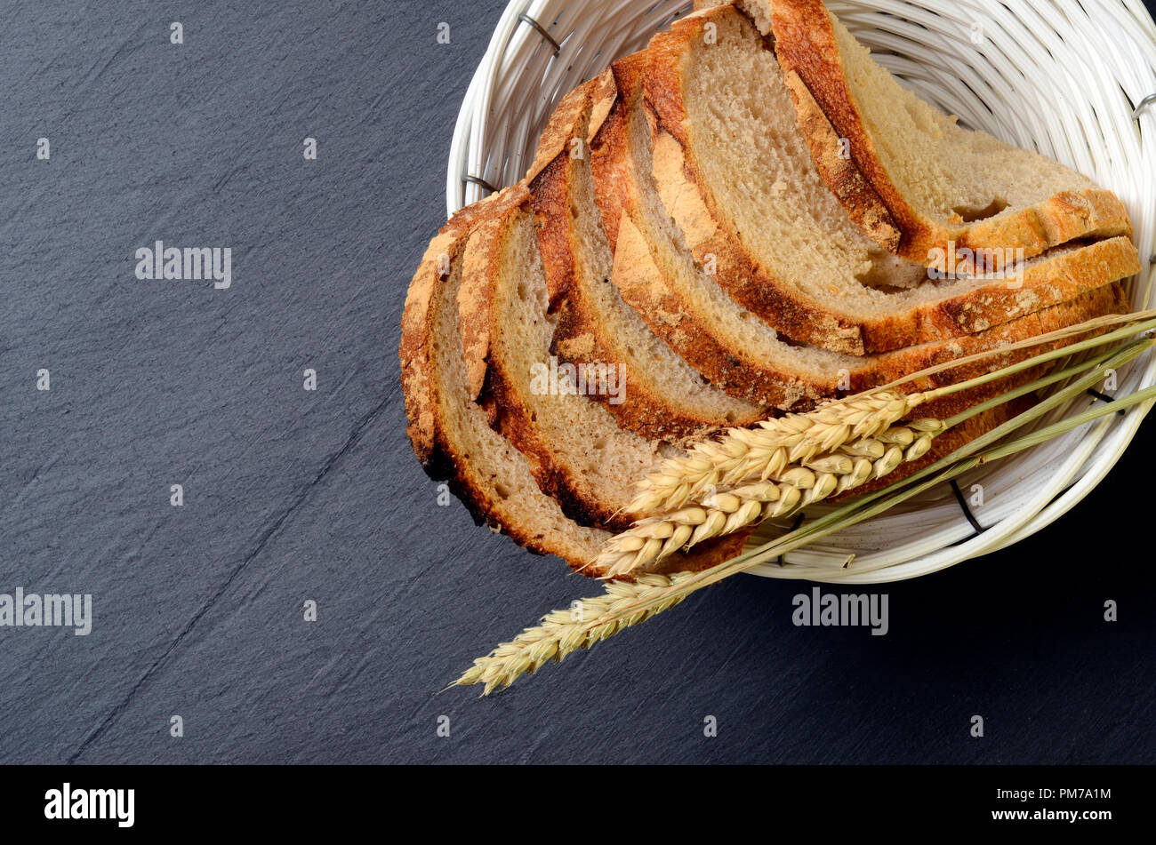 Tranches de pain rustique dans le panier et les épis de blé, le conseil d'ardoise Banque D'Images