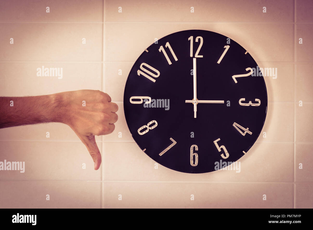 Big Black horloge de mur blanc. Changement d'heure. Le changement d'heure. Enquête auprès de l'Union européenne sur la date de changement. Geste de désaccord . Le pouce de l'homme de race blanche. Banque D'Images