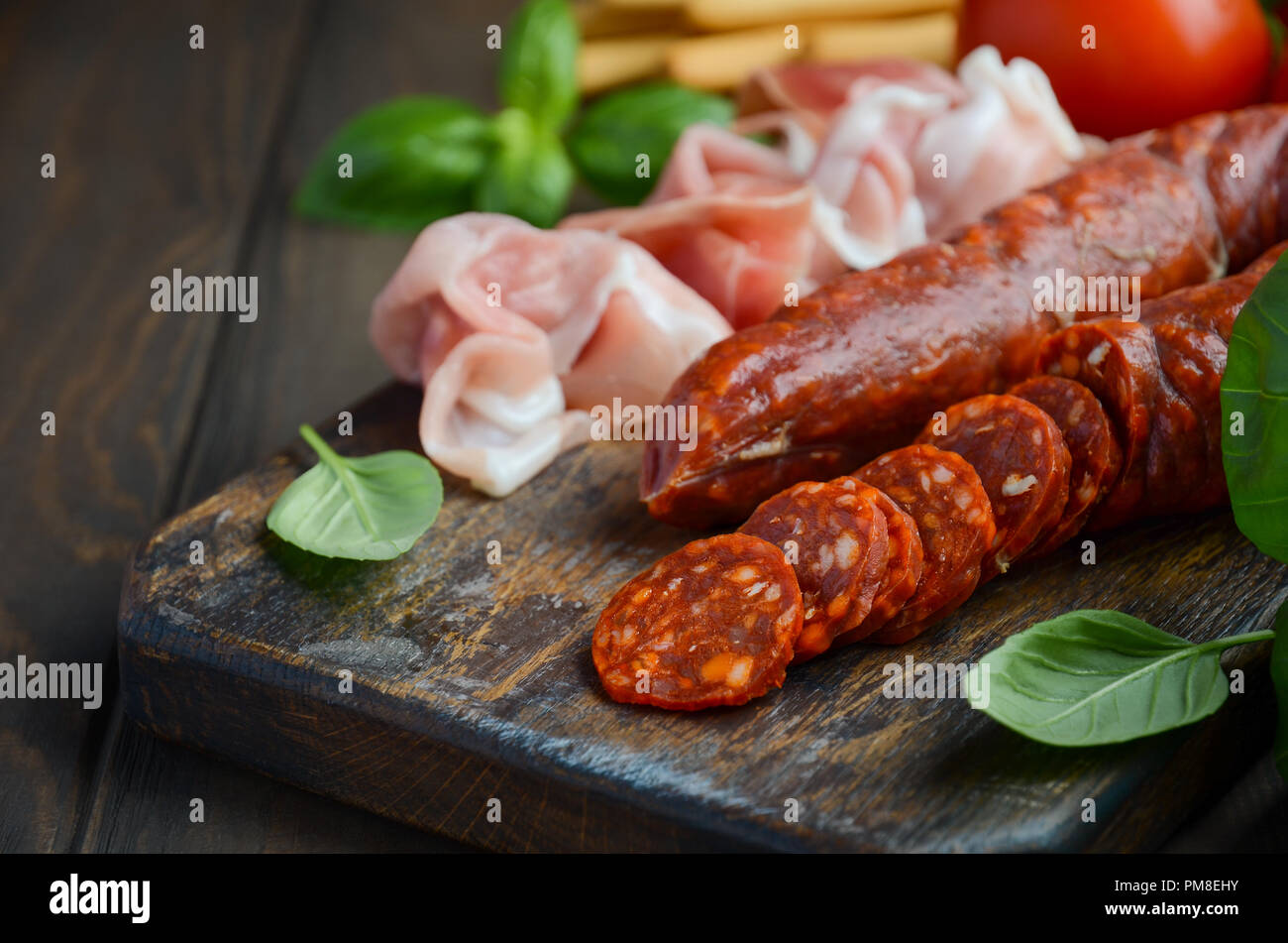 Saucisson Chorizo. Chorizo traditionnel espagnol avec des herbes fraîches et des tomates. Banque D'Images