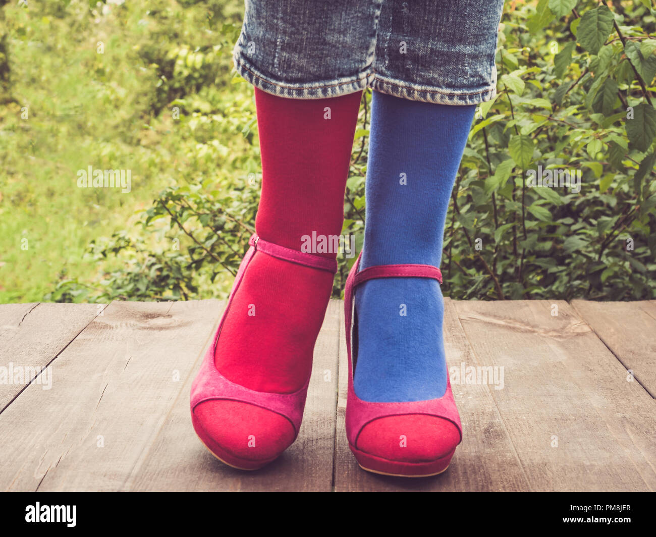 Les jambes des femmes en chaussures élégantes, lumineuses, varié, chaussettes multicolores sur la terrasse en bois sur l'arrière-plan d'arbres verts. Lifestyle, Fashion, Bea Banque D'Images