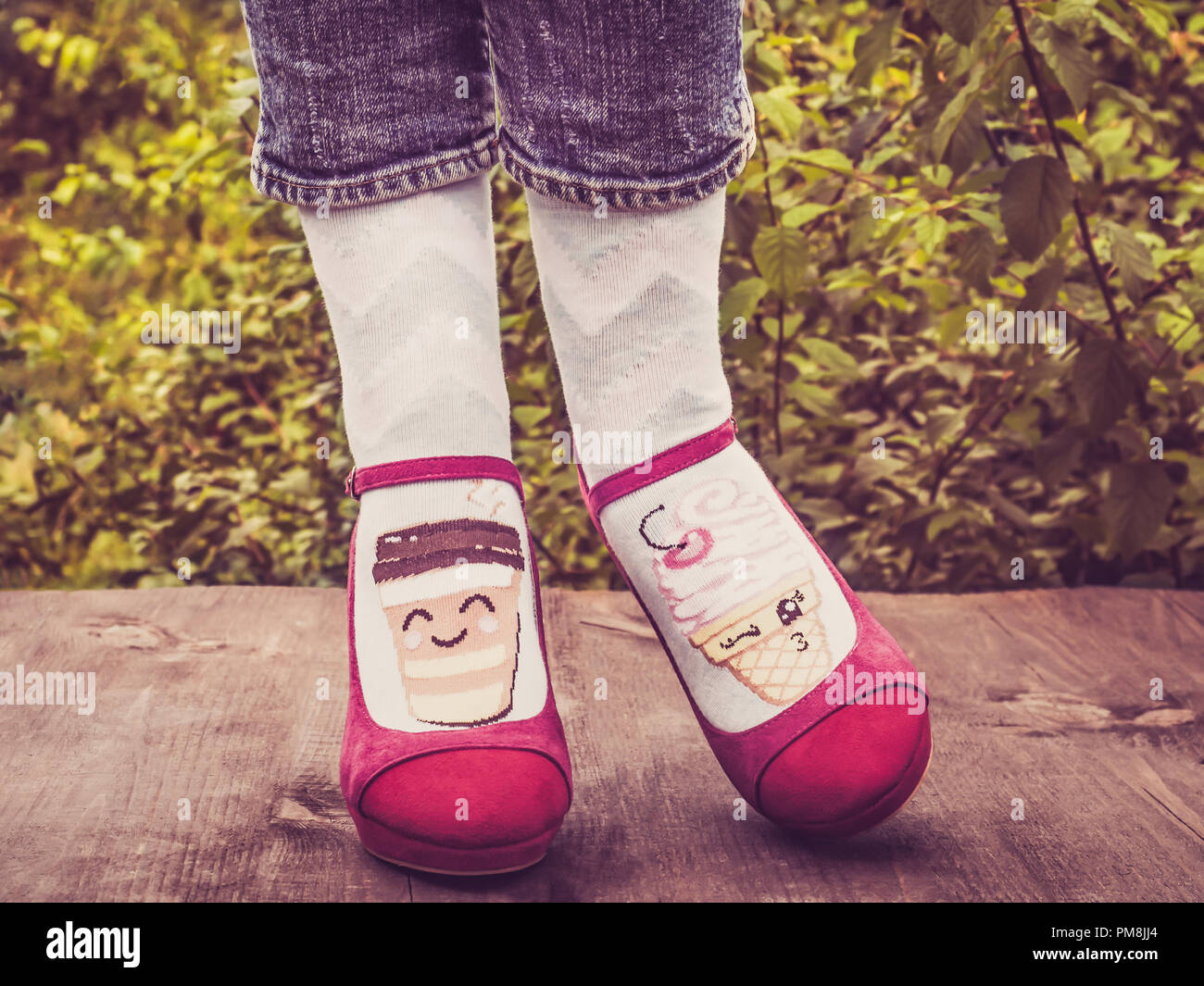 Les jambes des femmes en chaussures élégantes, lumineuses, varié, chaussettes multicolores sur la terrasse en bois sur l'arrière-plan d'arbres verts. Lifestyle, Fashion, Bea Banque D'Images