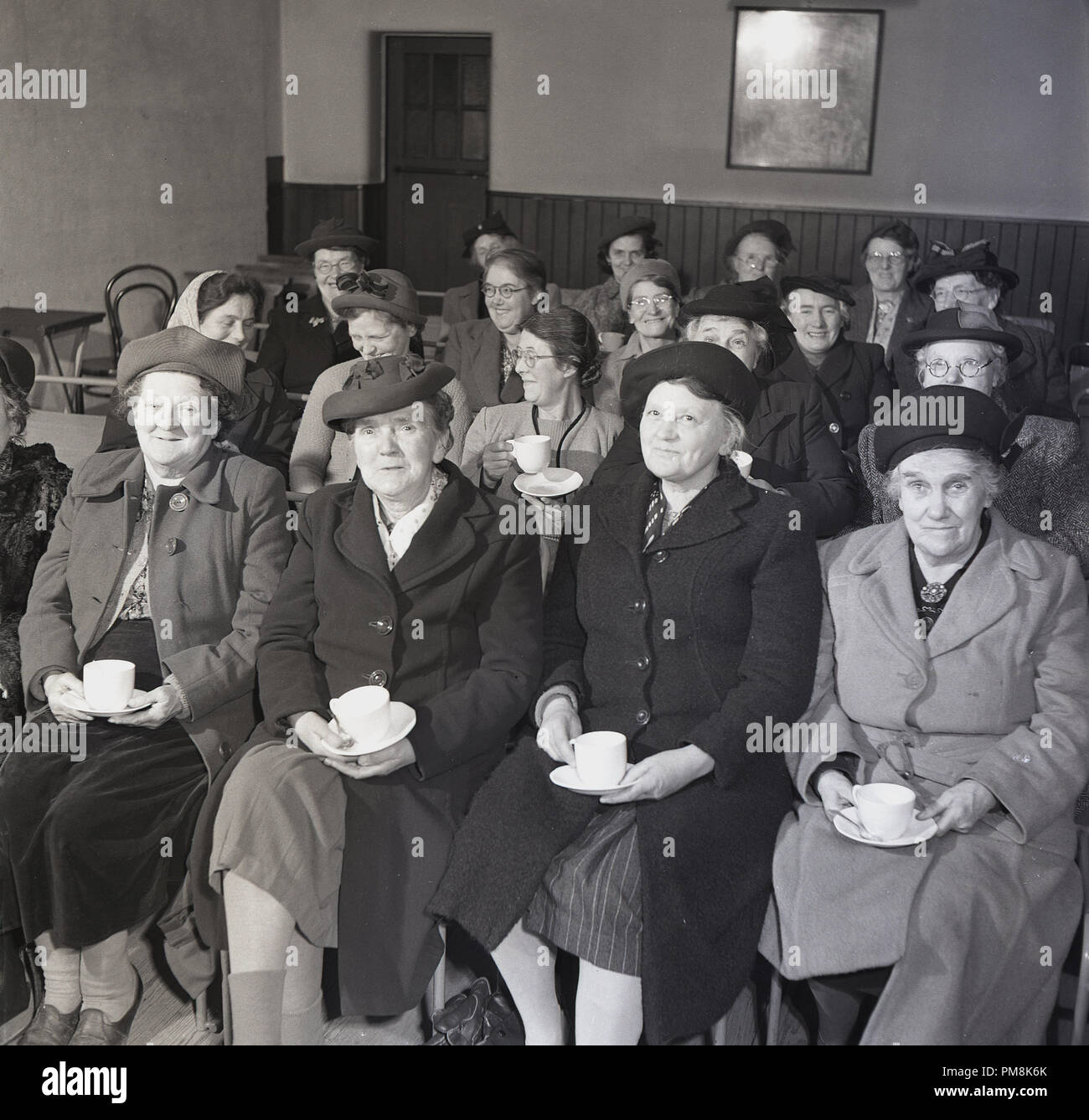 Années 1950, historique, un groupe de dames âgées, assis sur des tuniques, à l'intérieur d'un village hall ayant une tasse de thé, England, UK. Banque D'Images