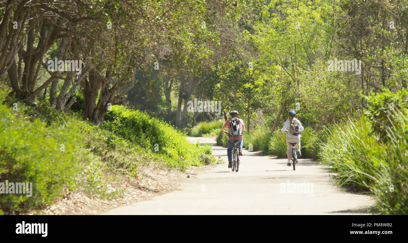 Caucasian couple riding bikes active dans un parc Banque D'Images