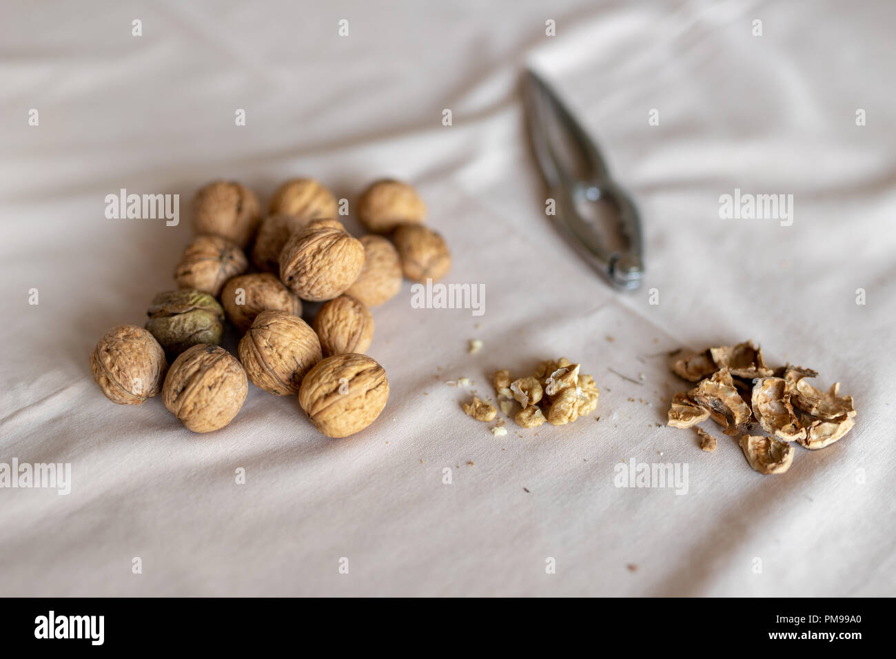 Casse-noisette et les noix dans un bol sur une table couverte d'une nappe. En-cas sur la table de cuisine. Fond clair. Banque D'Images