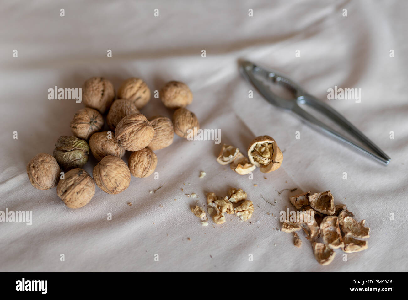 Casse-noisette et les noix dans un bol sur une table couverte d'une nappe. En-cas sur la table de cuisine. Fond clair. Banque D'Images