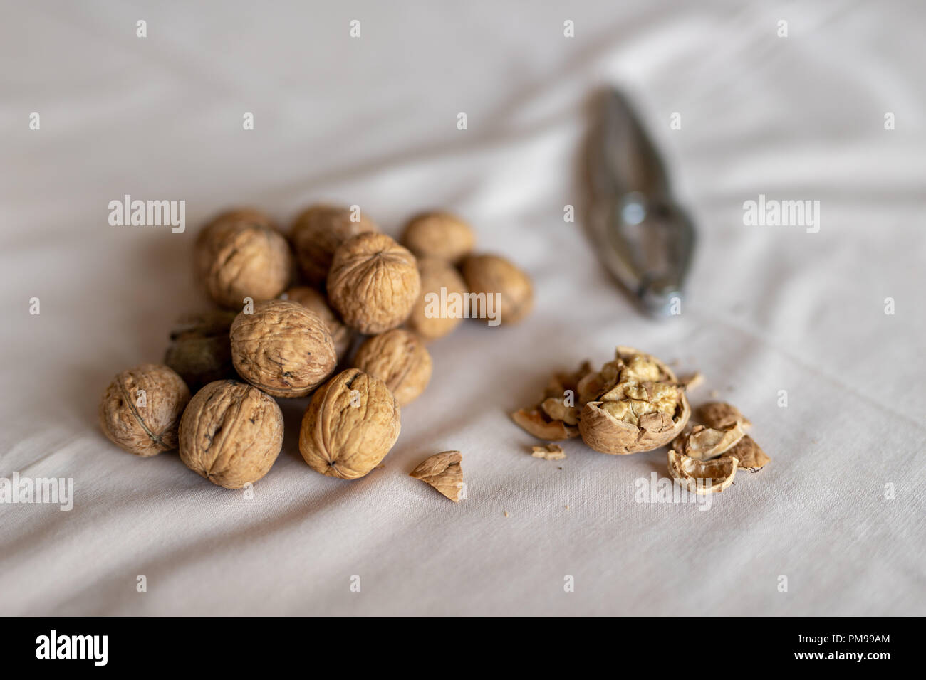 Casse-noisette et les noix dans un bol sur une table couverte d'une nappe. En-cas sur la table de cuisine. Fond clair. Banque D'Images