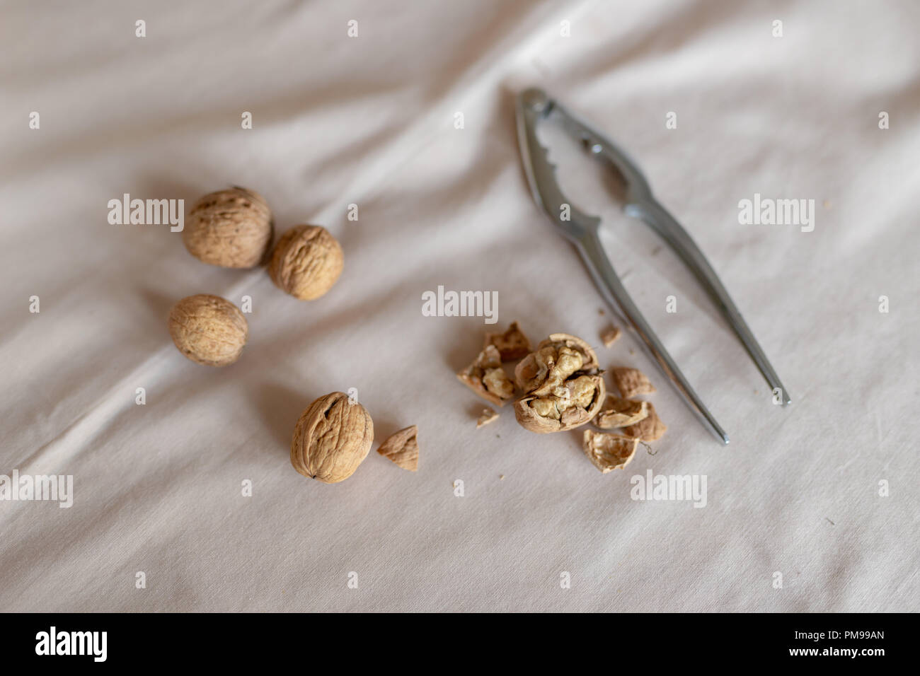 Casse-noisette et les noix dans un bol sur une table couverte d'une nappe. En-cas sur la table de cuisine. Fond clair. Banque D'Images