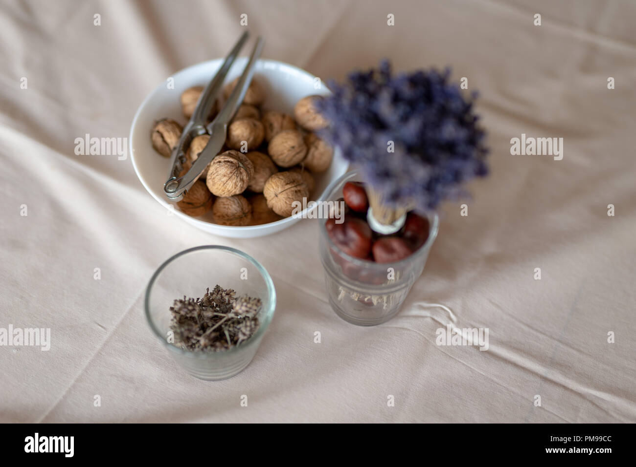 Casse-noisette et les noix dans un bol sur une table couverte d'une nappe. En-cas sur la table de cuisine. Fond clair. Banque D'Images