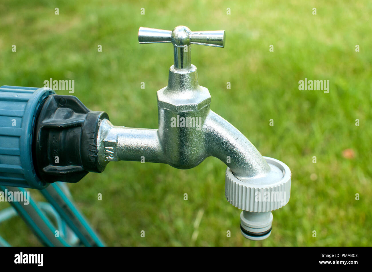 Un robinet d'eau avec tuyau de jardin en plastique gros plan sur  l'adaptateur jardin fond d'herbe verte Photo Stock - Alamy