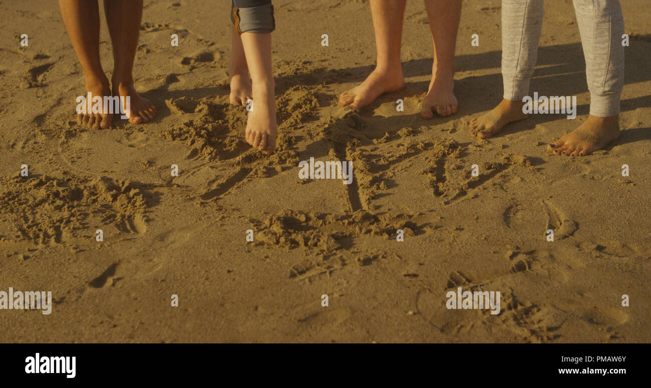 Des amis à l'aide de leurs pieds pour écrire sur la plage Banque D'Images