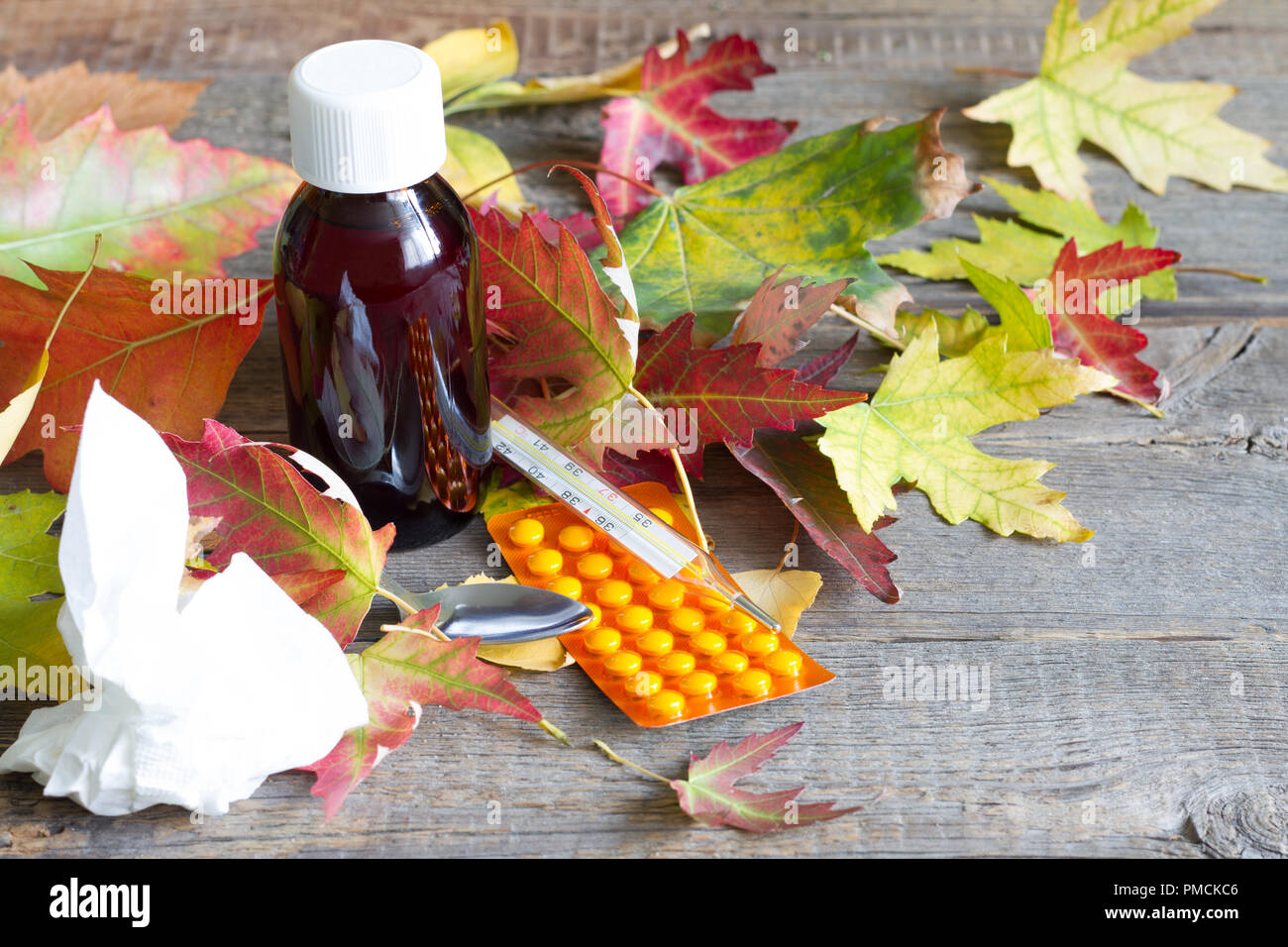 Comprimés médecine et thermomètre avec les feuilles d'automne froid et concept de traitement de la grippe Banque D'Images