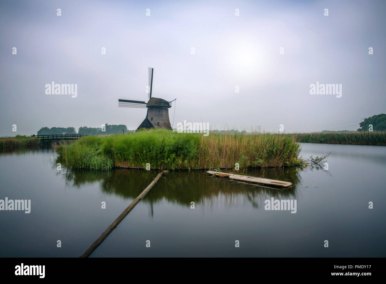 Ancien moulin à vent hollandais avec une rivière qui coule dans un paysage par matin froid près d'Amsterdam, Pays-Bas. Longue exposition. Banque D'Images