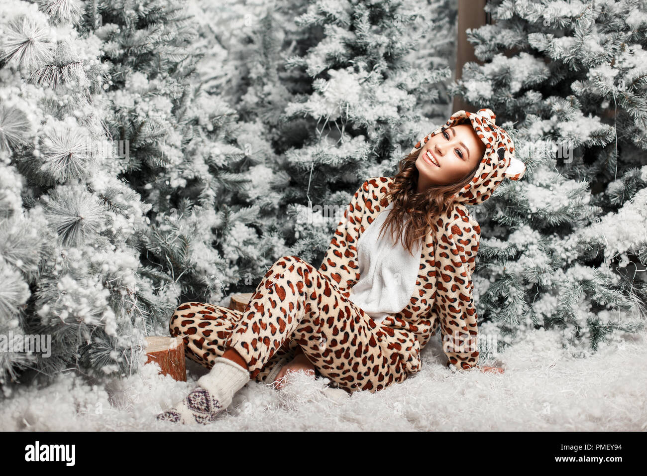 Funny happy belle femme avec un sourire dans un quartier branché de pyjamas ours près d'un arbre de Noël avec de la neige dans le studio Banque D'Images