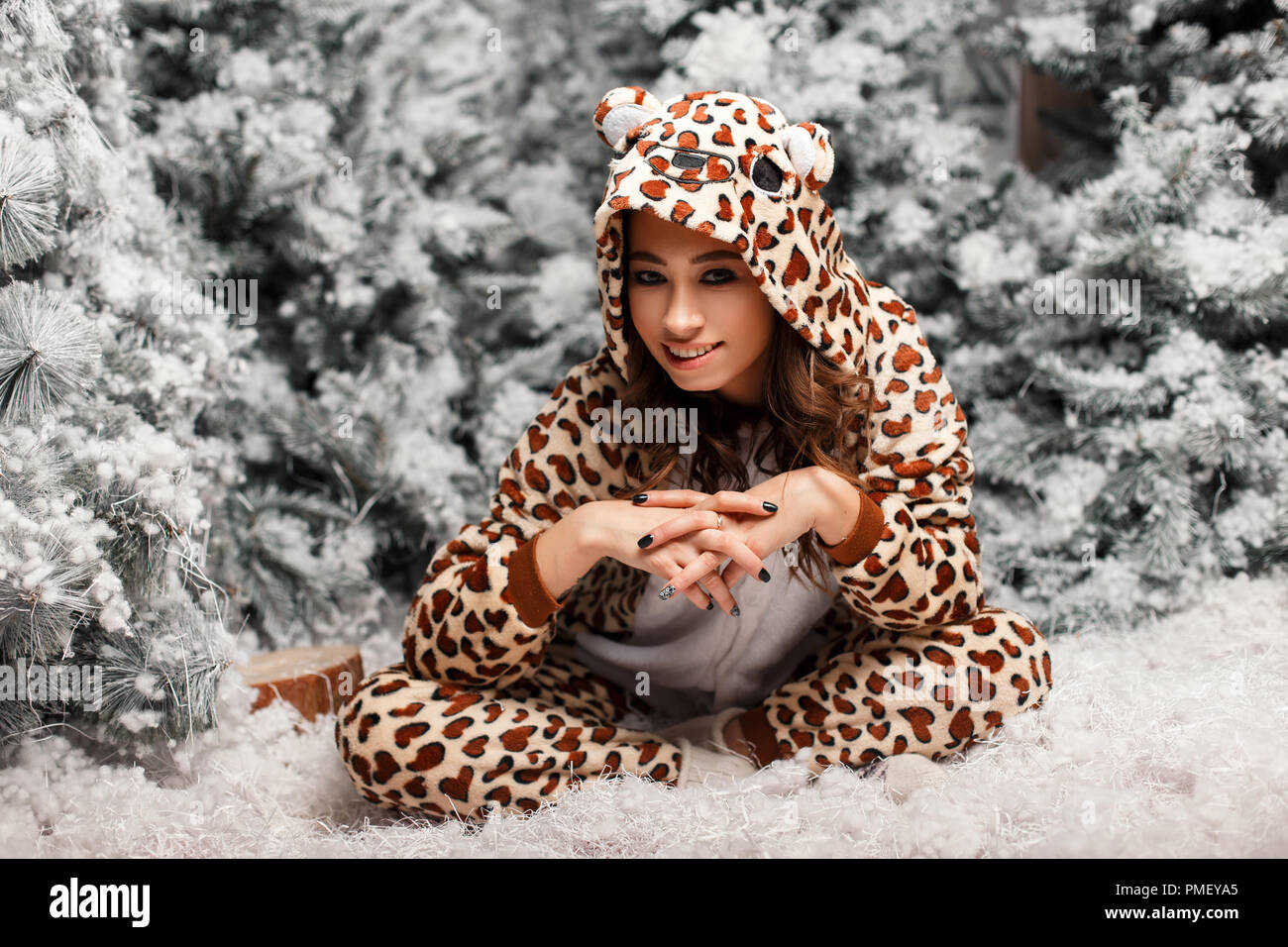 Belle jeune femme en pyjama funny assis près d'un arbre de Noël avec de la neige Banque D'Images