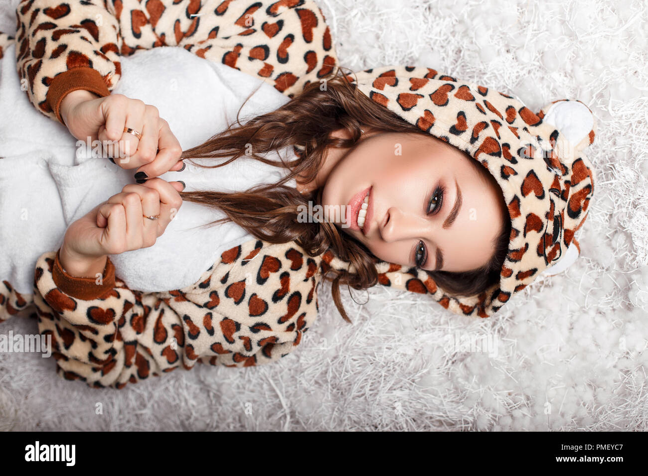 Jeune fille modèle dans un drôle d'ours en peluche vêtu d'un pyjama à capuchon. Soins de la peau Banque D'Images