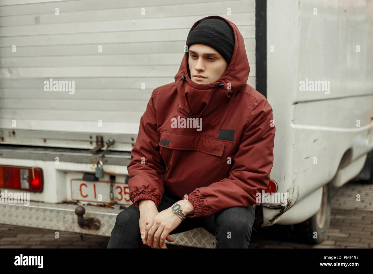 Beau jeune homme élégant dans un quartier chic avec une veste rouge black  hat assis près de la van Photo Stock - Alamy