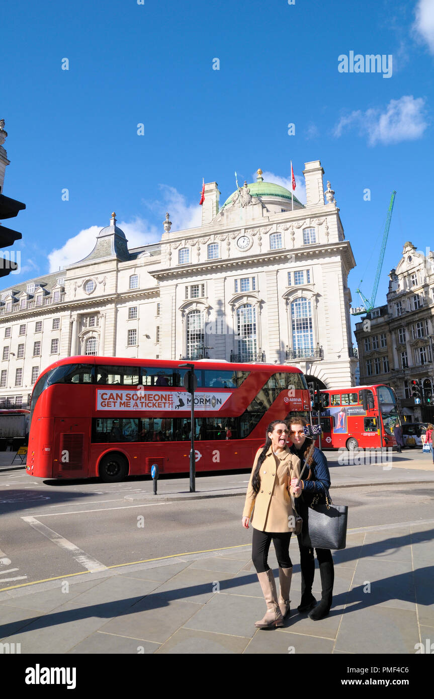 Deux adolescentes habillés de prendre une photo avec un bâton selfies à Piccadilly Circus, à des séjours à l'hôtel Cafe royal sur Regent Street, à Londres. Banque D'Images