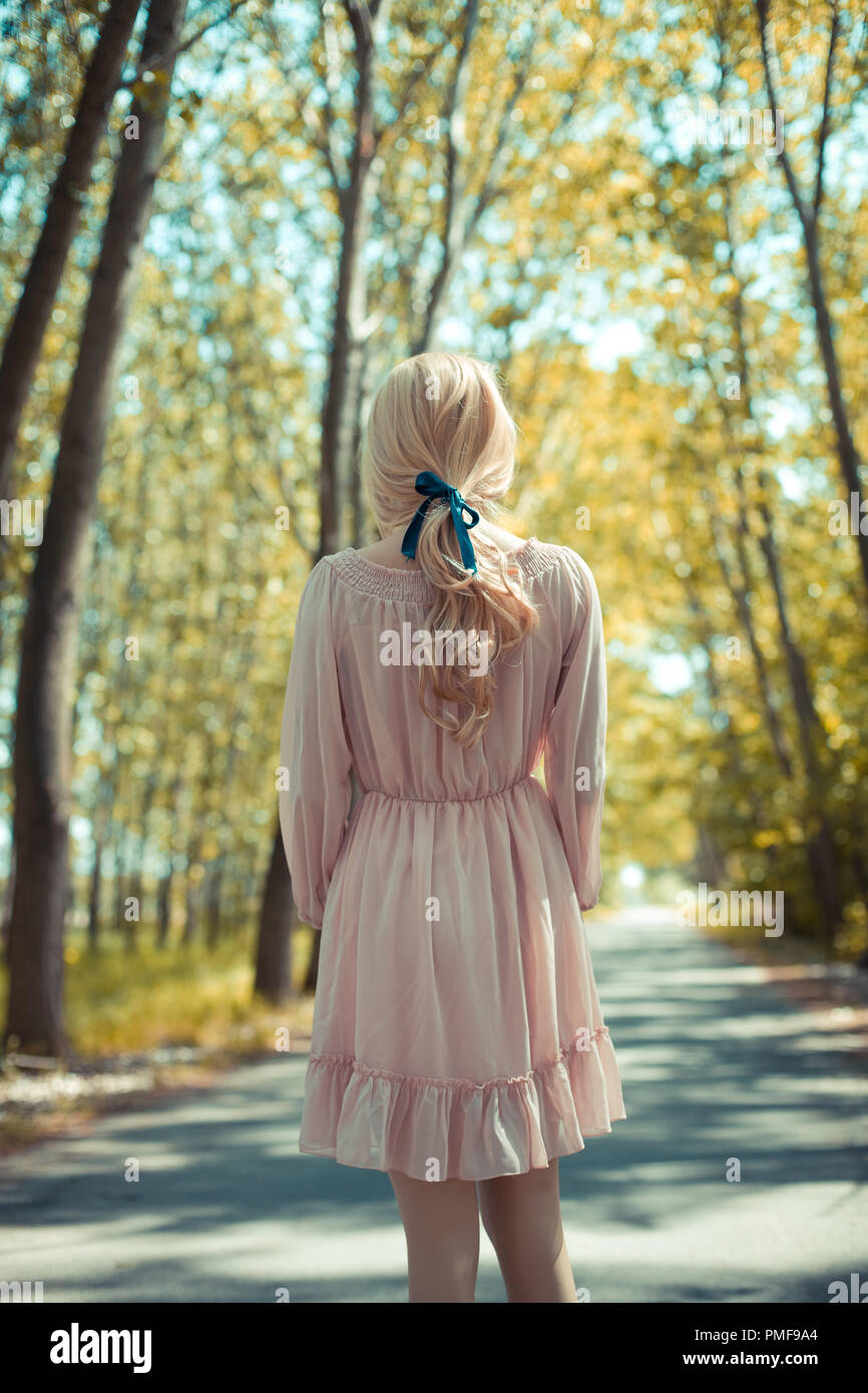 Femme blonde en robe rose debout à l'automne country road Photo Stock -  Alamy