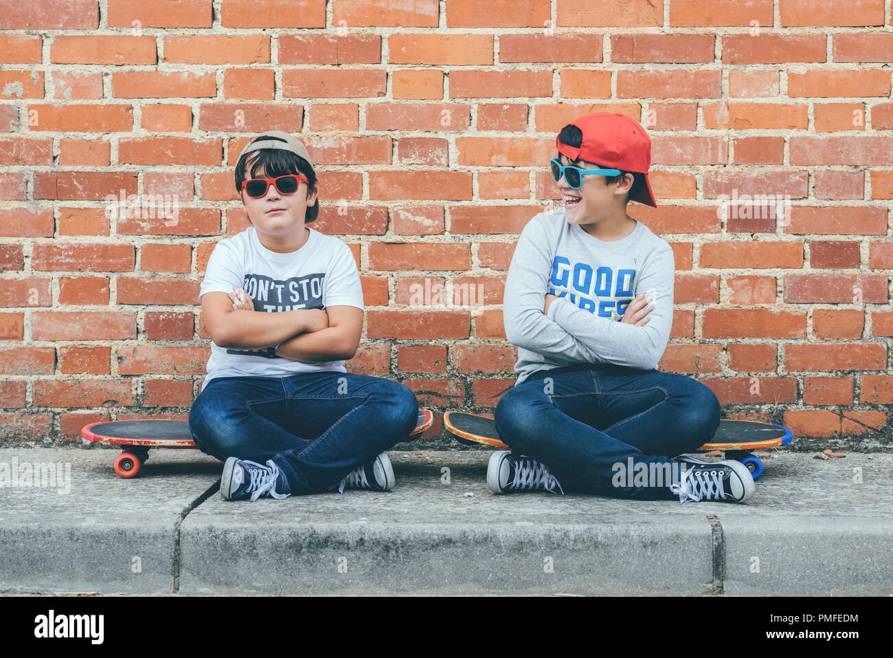 Les enfants avec une planche à roulettes et des lunettes de soleil dans la rue Banque D'Images