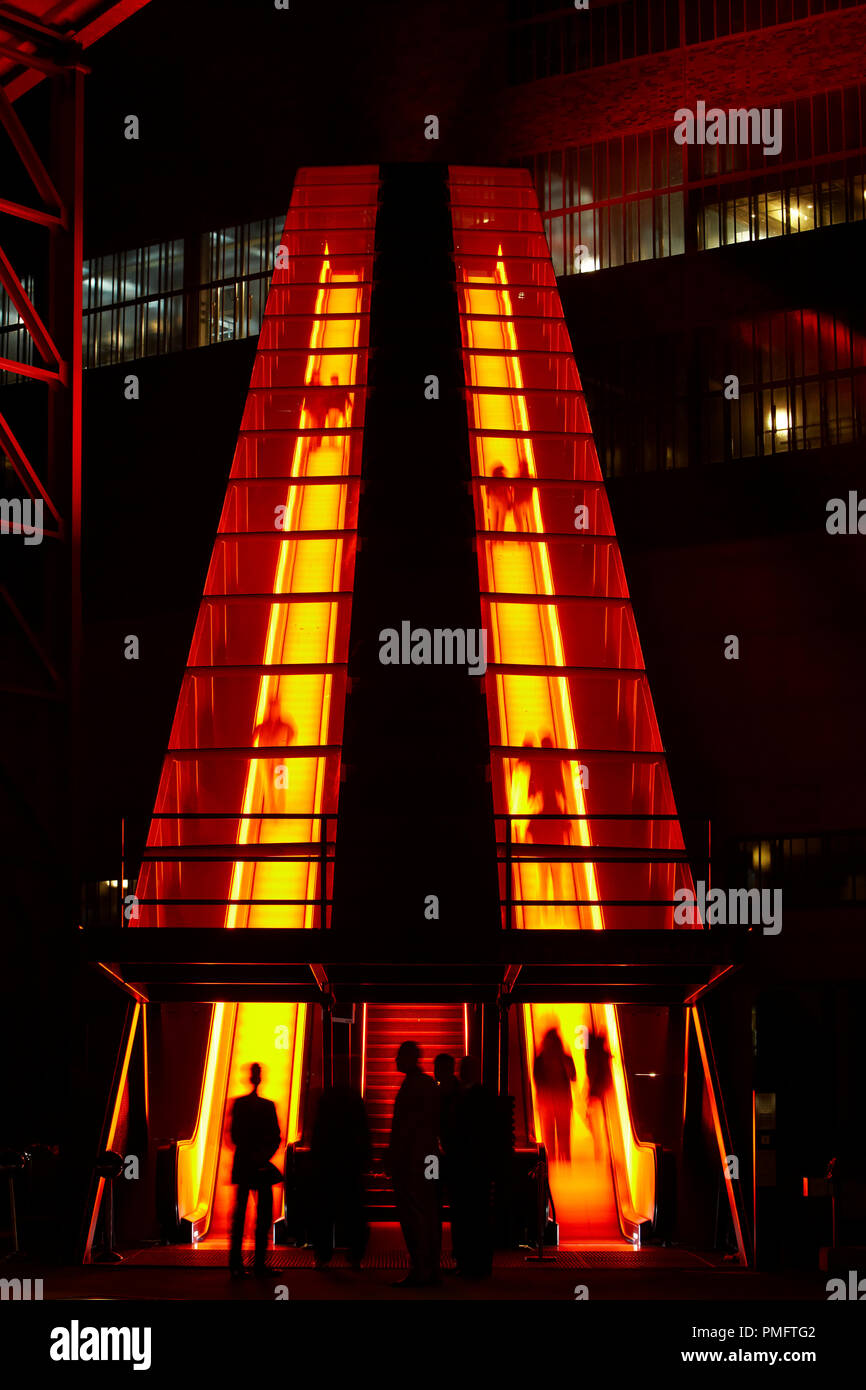 Escalator pour l'ancienne mine de charbon de Zollverein sur le lavage de rappelle en acier brillant sur un horizon mobile de rue. Au début du crépuscule, le bâtiment de l'éclairage du patrimoine culturel mondial de l'UNESCO commence. Banque D'Images