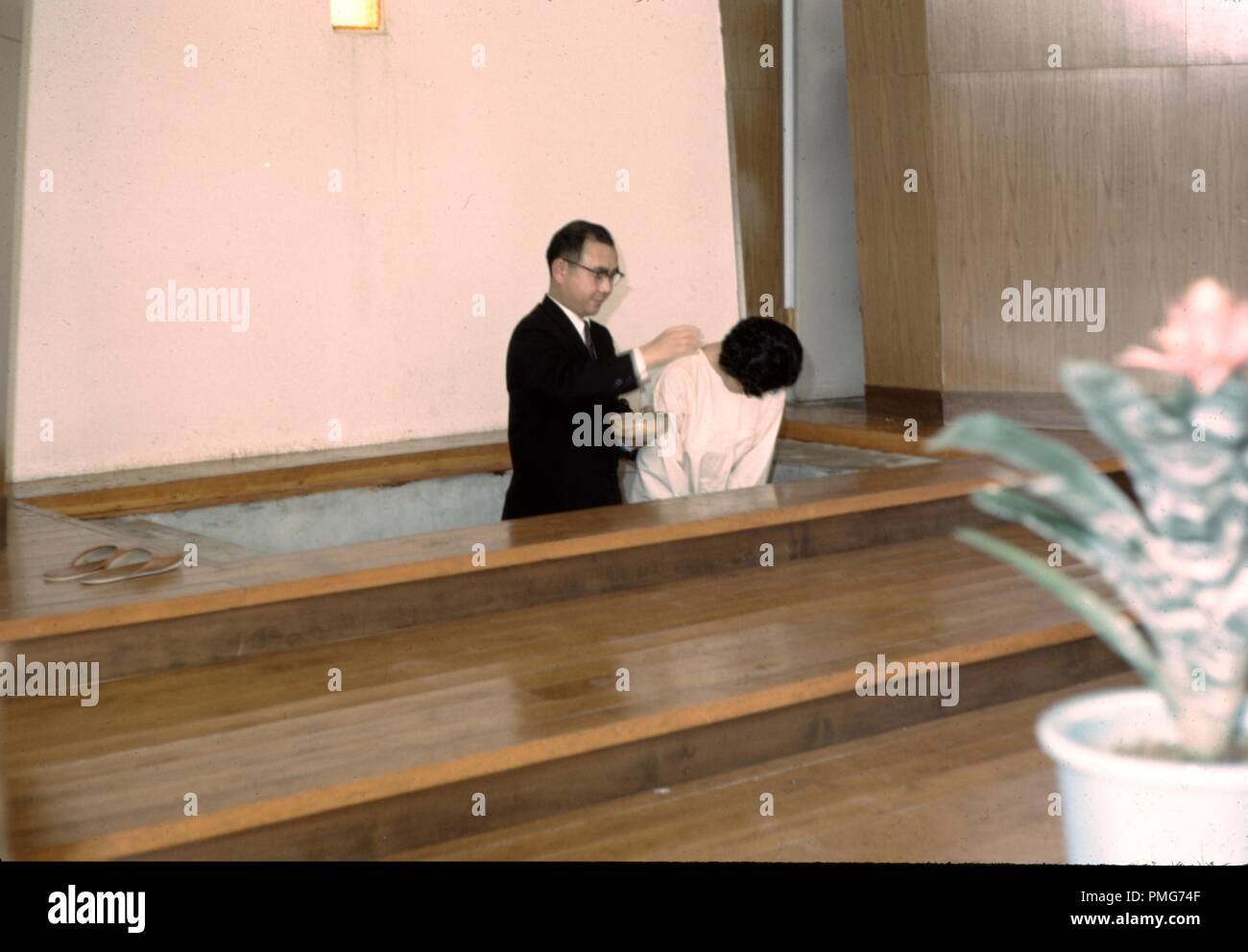Prêtre baptisant une japonaise, qui s'incline la tête, dans une Eglise missionnaire chrétienne dans le japon d'après-guerre, 1965. () Banque D'Images