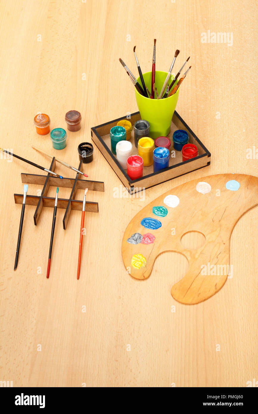 Palette en bois avec imposition de peintures et pinceaux avec tasse sur le bureau Banque D'Images