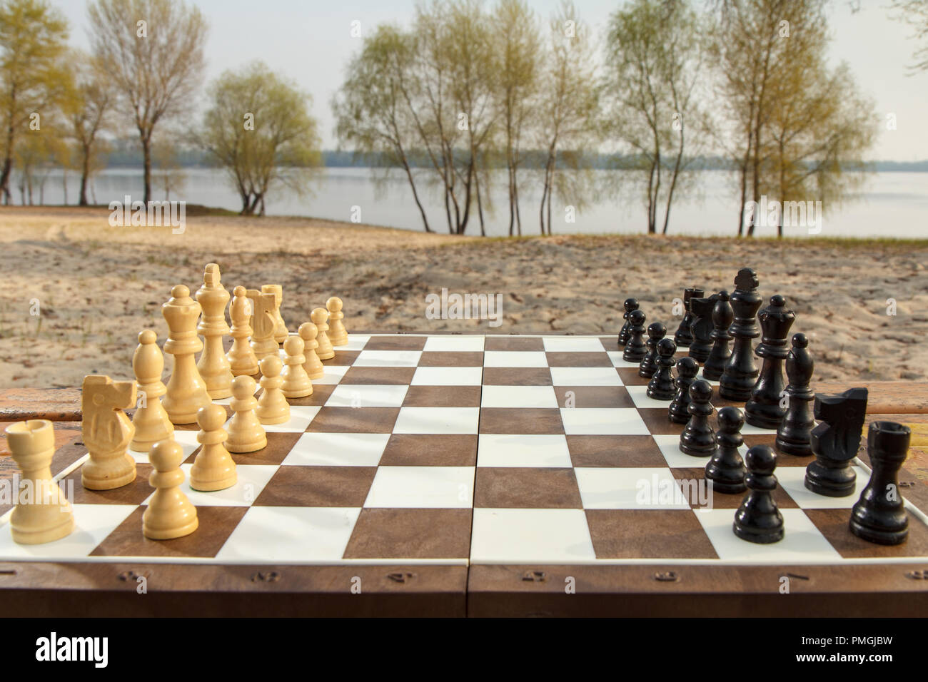 Conseil d'échecs avec pièces d'échecs sur le fond de la rivière. Jeu d'extérieur en bois avec pièces d'échecs Banque D'Images