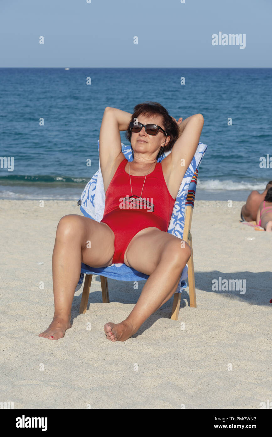 Italie Calabre femme d'âge moyen à la mer assis sur un lit de bronzage 2 Banque D'Images