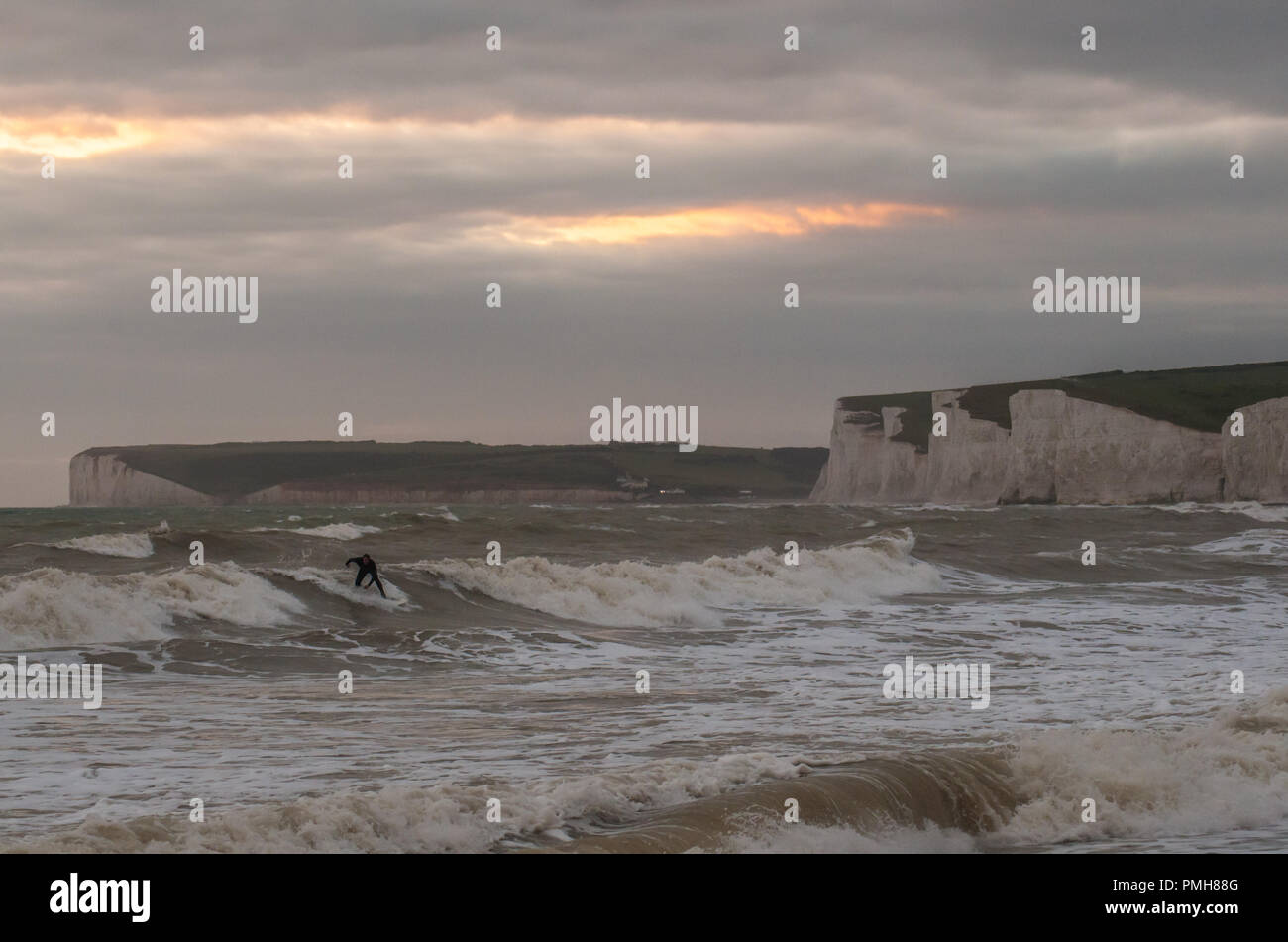 Birling Gap, Eastbourne, East Sussex, Royaume-Uni..18 septembre 2018..L'Augmentation du vent fait monter les vagues au large de la côte sud. Le surfeur fait une vague avec Sept falaises de craie Sisters en arrière-plan Banque D'Images