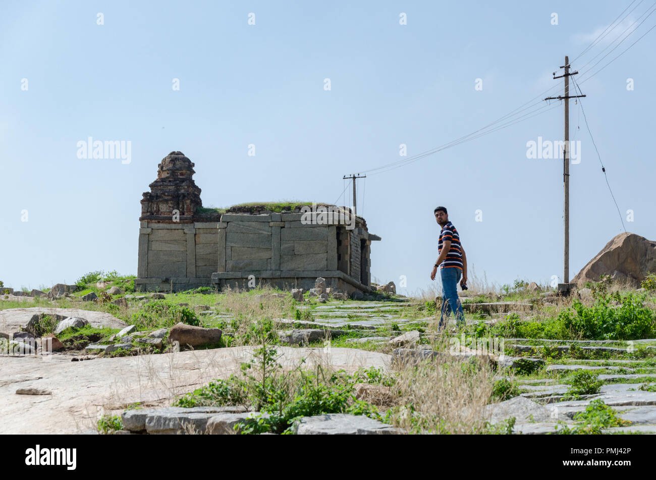 Garçon à dos en marchant vers un monument situé sur Hemakuta Hill de Hampi, Karnataka, Inde. Banque D'Images