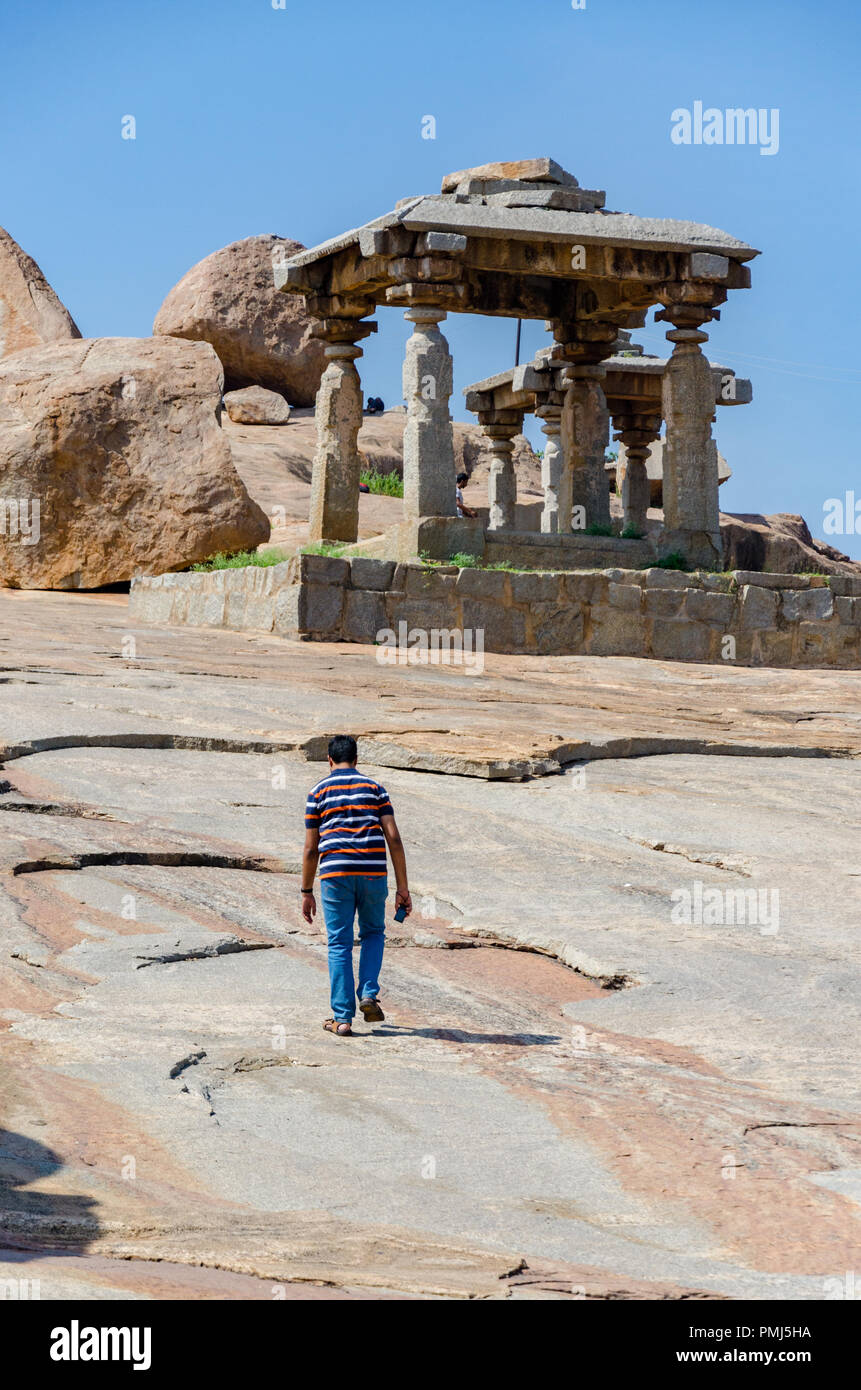 Lone boy walking près d'énormes rochers et de structures de pierre sur l'Hemakuta Hill Hampi, Karnataka, Inde Banque D'Images