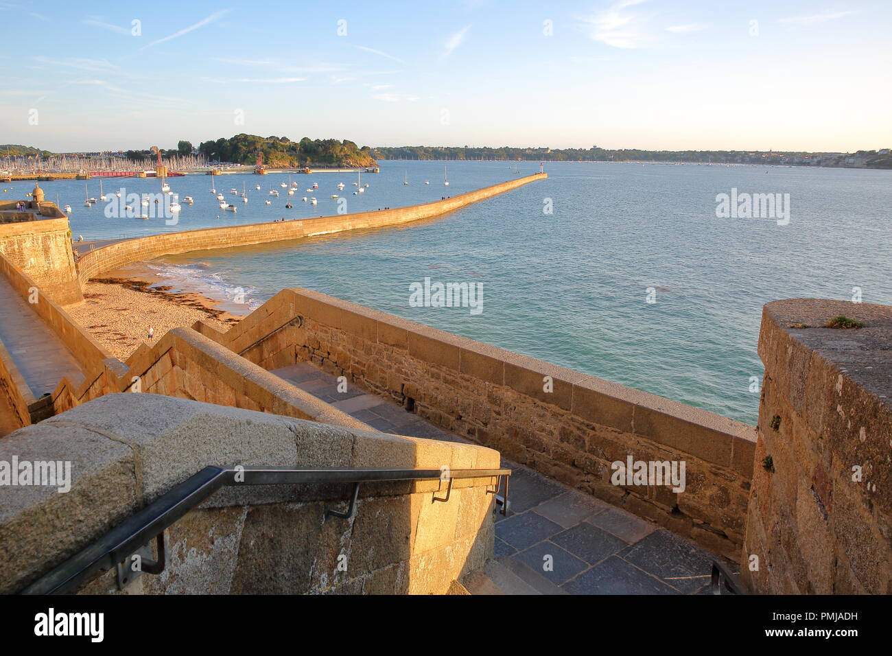 Les remparts de la ville fortifiée de Saint Malo au coucher du soleil grâce à la jetée (mole des Noires) et le port en arrière-plan, Saint Malo, Bretagne, France Banque D'Images