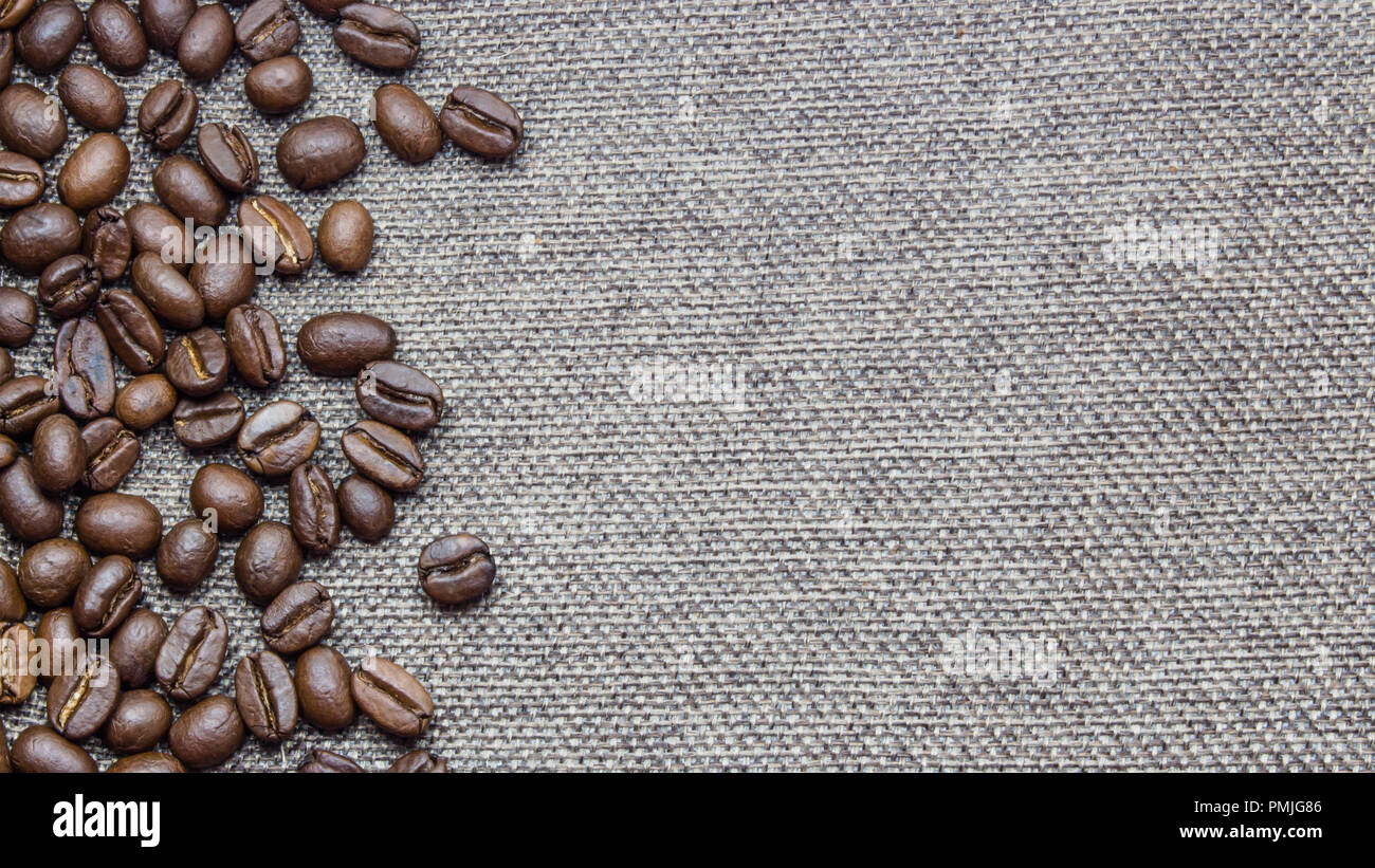 Les grains de café torréfiés répartis autour de la jute texture background. Copie disponible avec l'espace. Banque D'Images