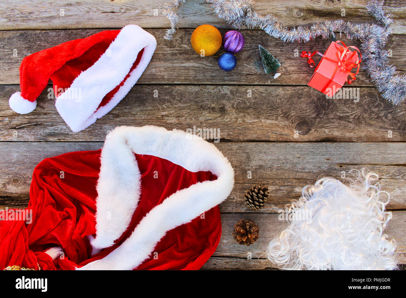 Costume Père Noël, petit arbre, pomme de pin, des boules de Noël, guirlande, cadeau sur fond de bois. Vue d'en haut. La tonalité de l'image. Banque D'Images