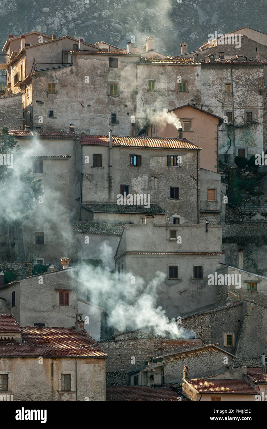 Le petit village touristique d'Ortona dei Marsi rétroéclairé par la première lumière d'hiver avec la fumée sortant des cheminées des maisons.Abruzzes Banque D'Images