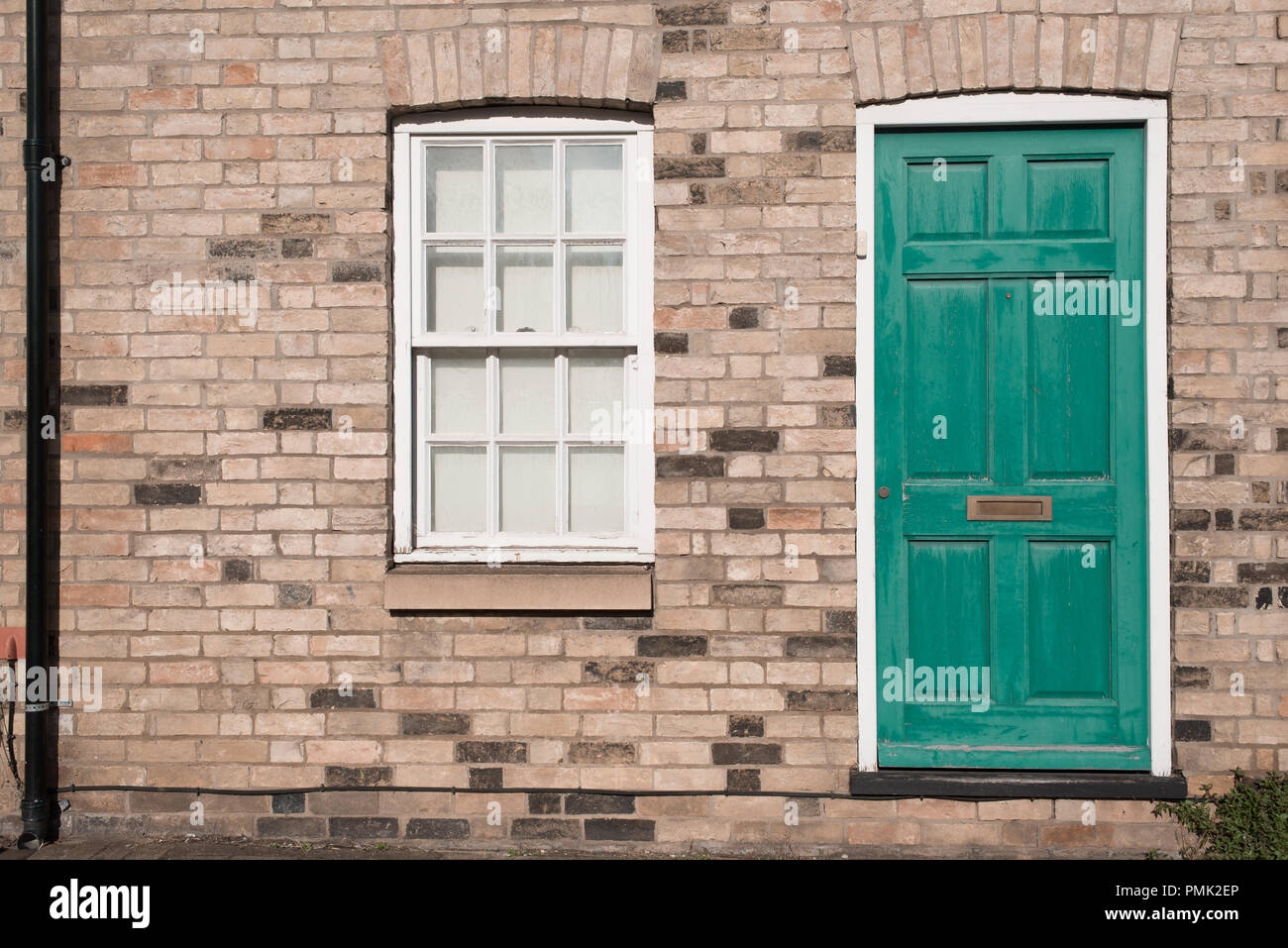 Vintage pastel vert porte sur un mur en brique restauré d'un bâtiment résidentiel maison géorgienne avec fenêtre à guillotine en bois blanc Banque D'Images