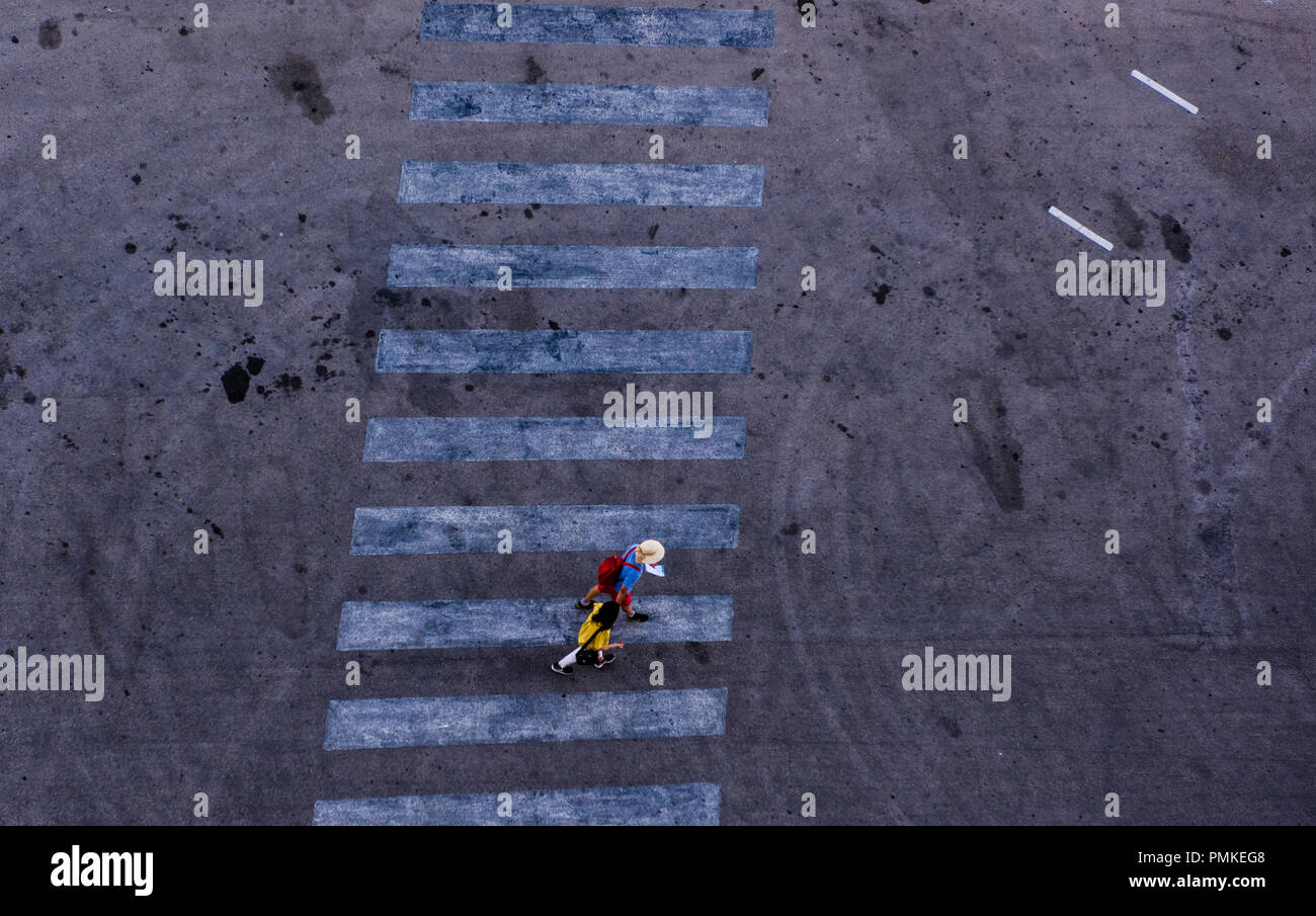 Couple walking on zebra crossing, entouré par hasard, creative patterns sur le tarmac, elevated view, Port de La Valette, Malte, Europe Banque D'Images