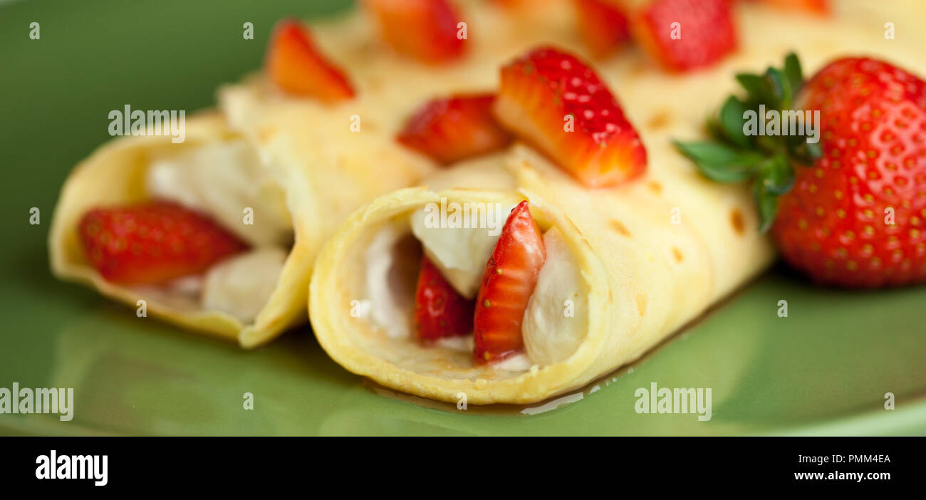 Crêpes aux fraises avec de la crème fouettée sur une plaque verte Banque D'Images