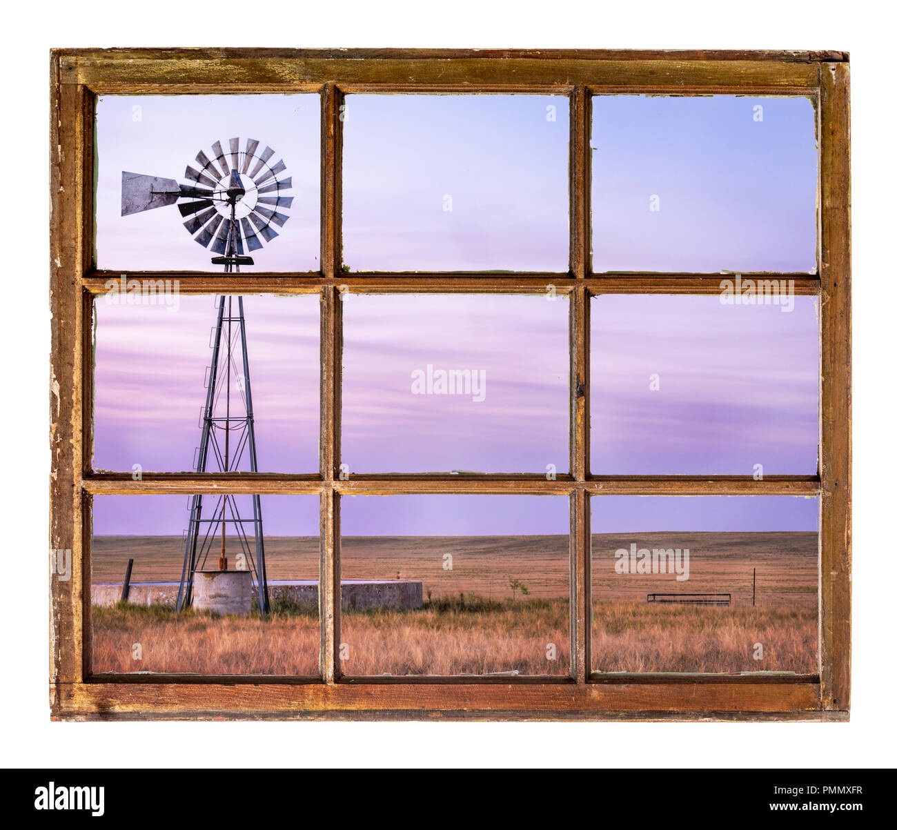 Moulin avec une pompe et réservoir d'eau du bétail dans les prairies à graminées courtes au crépuscule vue depuis une fenêtre de cabine vintage Banque D'Images
