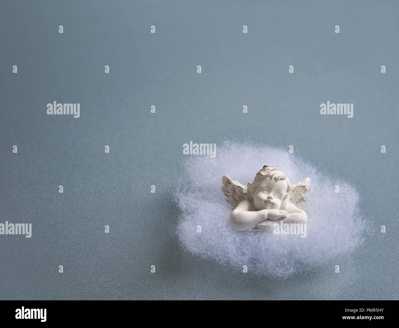 Un petit ange en coton sur une plaque de verre bleu-gris en verre dépoli Banque D'Images