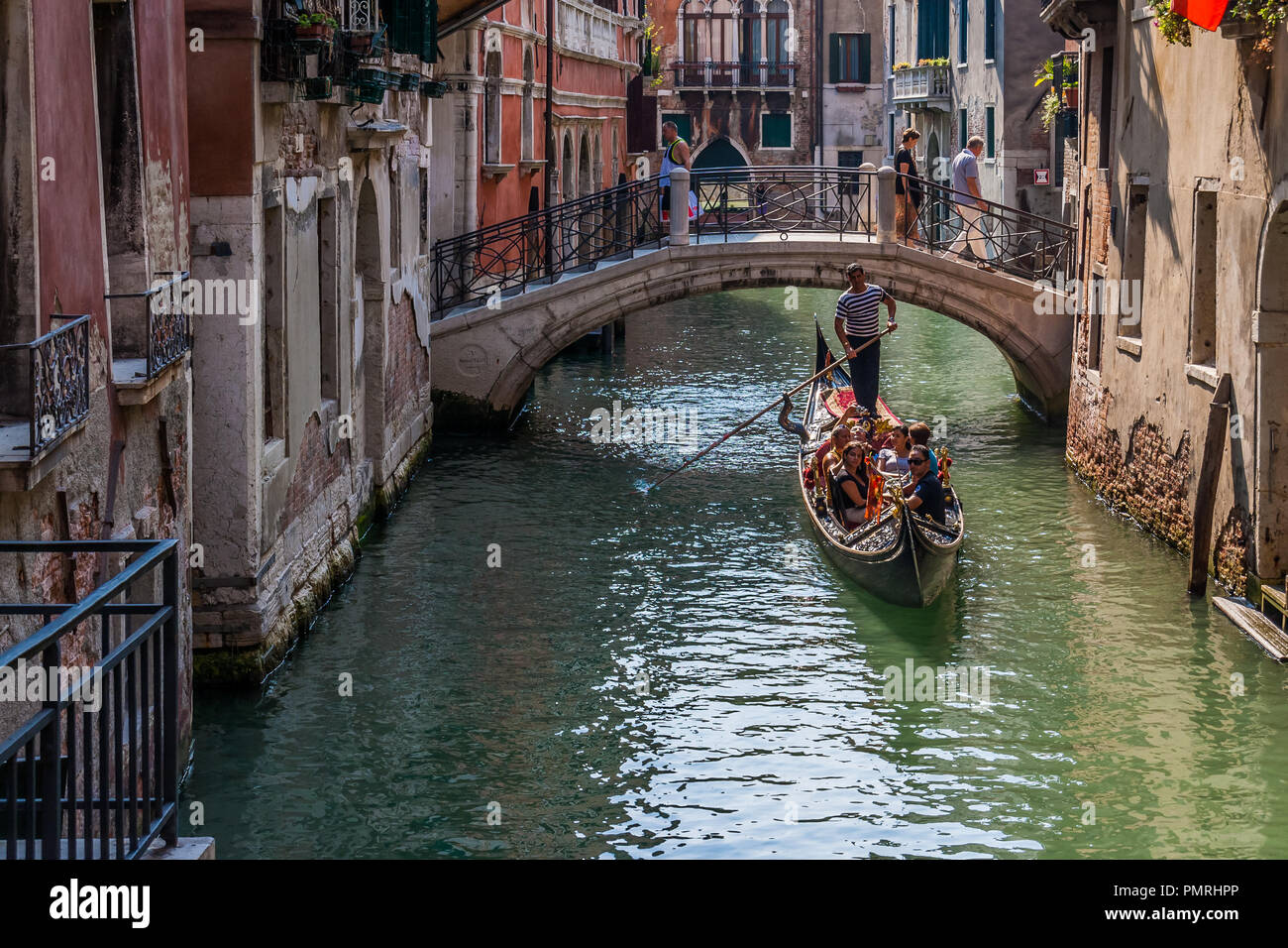 Les touristes qui gondole dans un petit canal à Venise, Italie. Banque D'Images